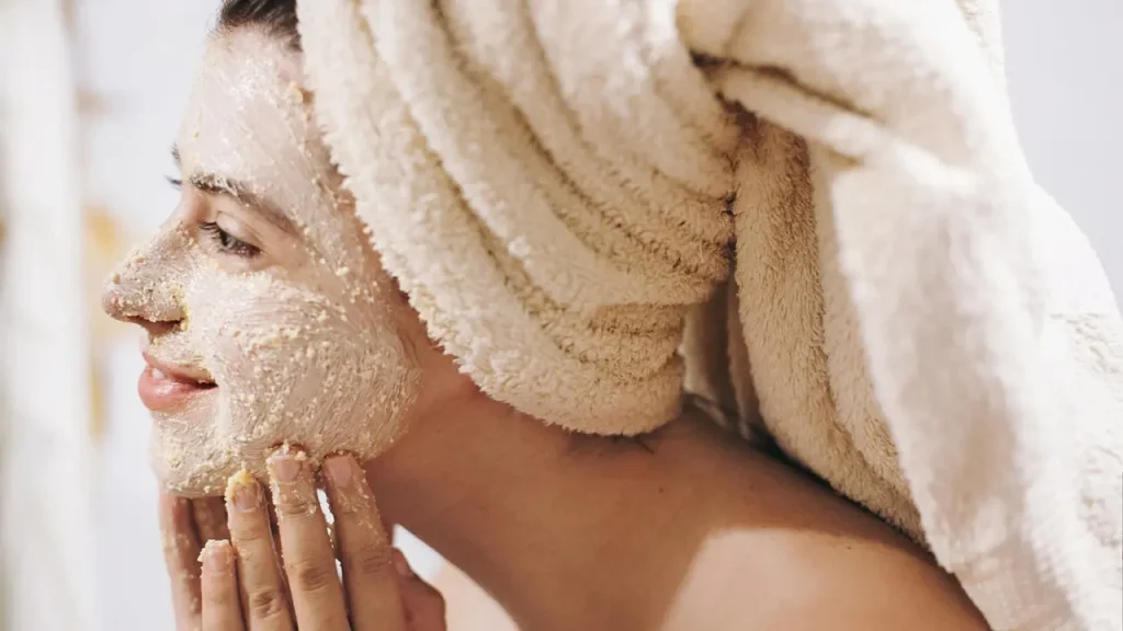 تصویر یک خانم که در حال استفاده از اسکراب صورت برای مراقبت از پوست چرب خود میباشد